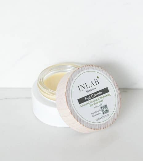 A jar of INLAB eye cream with a wooden lid, showcasing its creamy texture against a minimalist white background.