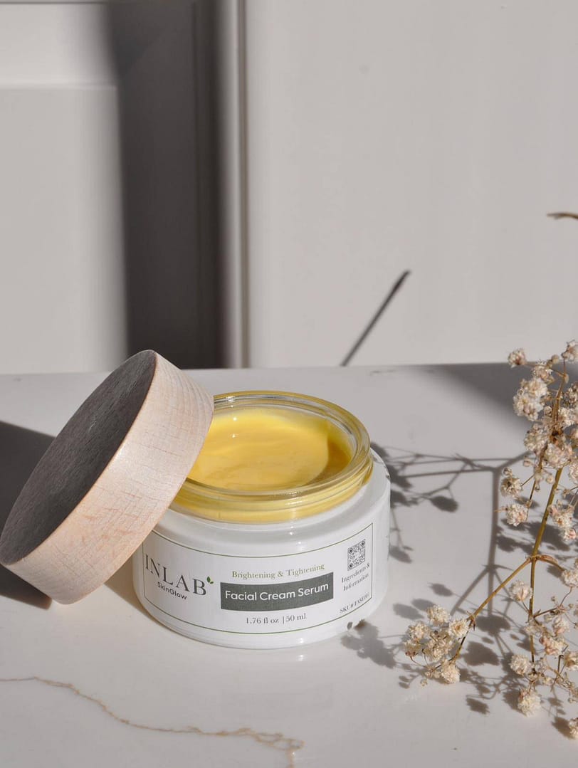 Open jar of "Deep Restore Night Cream" with rich yellow cream inside, styled with delicate dried flowers on a soft neutral background